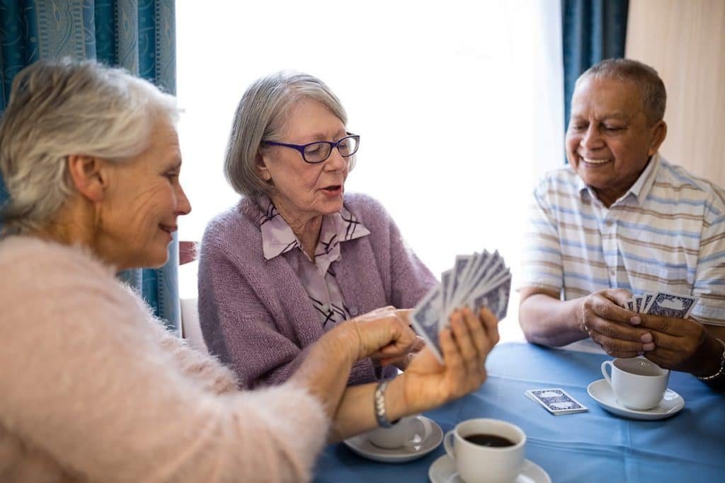 Trois seniors partagent une partie de cartes autour d'un café
